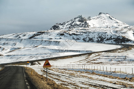 上坡路景观雪山与街道警告标志在冰岛图片