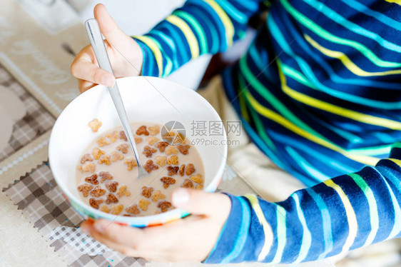 早餐或午餐吃自制麦片的孩子手的特写儿童健康饮食在托儿所学校食堂或家里碗特写镜头用牛奶和麦片拿图片