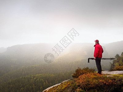 自然摄影师准备相机拍摄迷雾笼罩的秋天山脉的令人印象深刻的照片图片