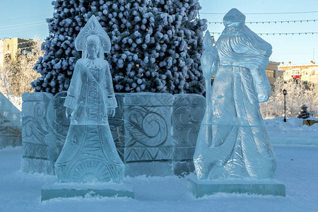 从圣诞树附近的冰面上雕刻的白雪女和圣图片