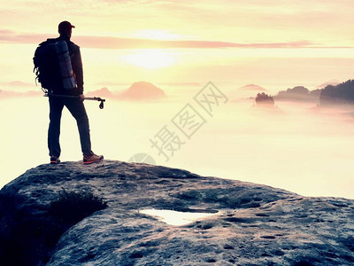 手持带杆子的木轮阳光春夏和导游留在山尖悬崖上在迷雾谷上空的岩石观察点图片