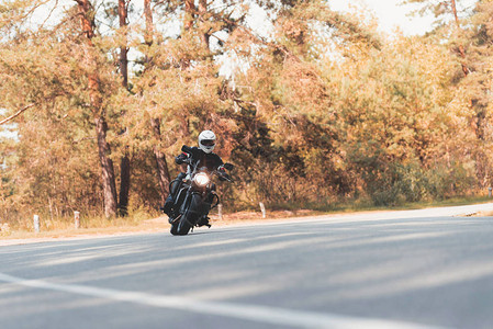 一名戴头盔的年轻人骑着电动摩托车在森林道路上骑马图片