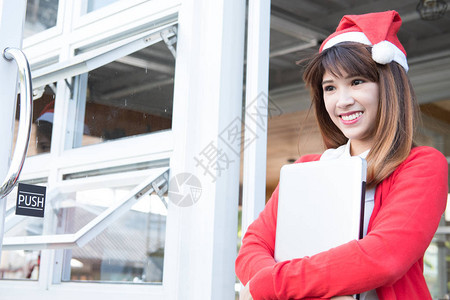 亚洲女人在她的商店里戴着圣诞老人的帽子图片