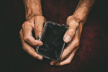老人手里拿着一个空钱包老式的空钱包在皱纹的手退休概念中的贫图片