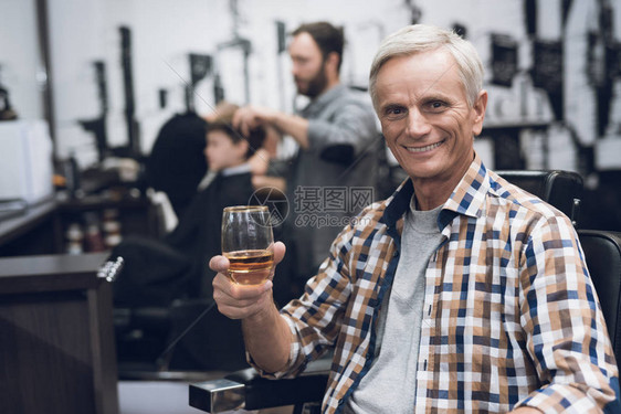 老人在理发店的理发椅上喝酒图片