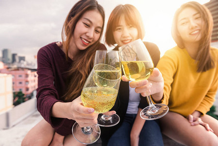 户外拍摄的年轻人在屋顶派对上举杯祝酒年轻的亚洲女孩朋友在外面喝酒节日庆典节日聚会青少年的生活方式派对自由和乐趣户外图片