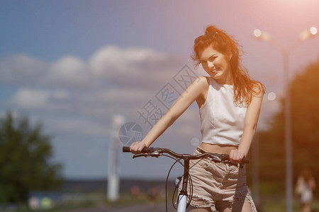 穿着短裤和上衣的红头发年轻女孩站着骑自行图片