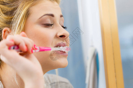 女人刷牙缝牙洗手间有牙刷的金发女孩看镜图片