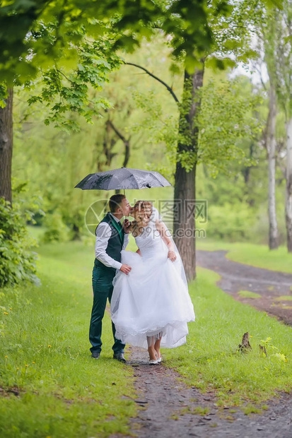 美丽的新娘和新郎在公园的雨伞下散步红头发新娘图片