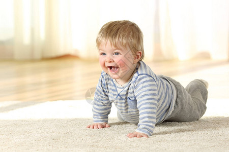 快乐的婴儿在家里的地毯上爬行图片