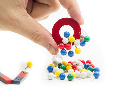 圆形红色和蓝色磁铁吸引金属纸针在白色的手隔离图片