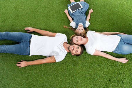 一家人在草地上躺着数字平板电脑的俯视图图片