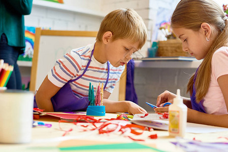 两个男孩和女孩在学校的艺术和工艺课上制作手工礼品卡的肖像图片
