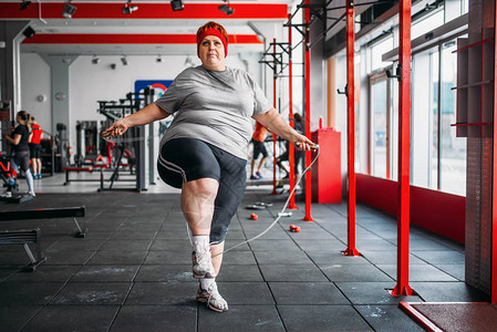 在健身房里抱着跳绳的胖汗女人图片