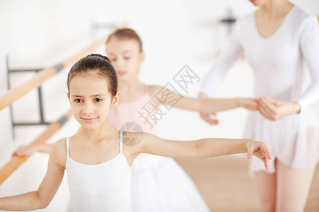 有吸引力的小芭蕾舞训练在教室与他们的老师帮助图片