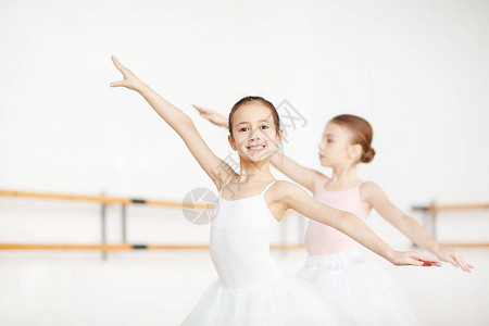 两个小女孩扩张区手臂而芭蕾课的训练图片
