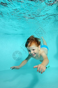 快乐的小男孩潜水水下到池底的和微笑肖像从水底垂直视图背景图片