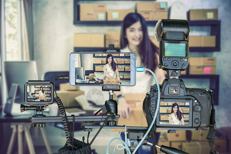 专业相机与智能手机和行动相机三脚架上的年轻亚洲青少年所有者商界女在家工作网上购物现场直播为企业家的概念图片