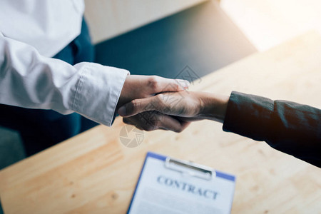 两个人握手在办公室里签合同图片