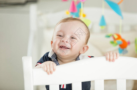 2颗牙齿站在婴儿床上的快乐微笑的男孩肖像图片