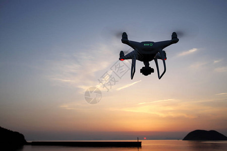 远程遥控无人机配备了高分辨率摄像机海水拍打的夕阳的天空飞翔图片