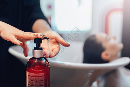 女理发师用洗发水美发沙龙清洗顾客头发美容工作室的发型制作工艺背景图片