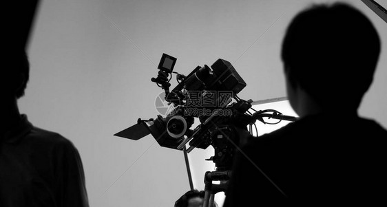 电影拍摄或视频拍摄制作的船员团队和专业设备如超级超高清数码相机与三脚架和照明设置演播室和黑白风格图片