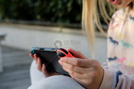 十几岁的女孩玩游戏的任天堂交换机控制台儿童手持任天堂开关户外绿屏图片