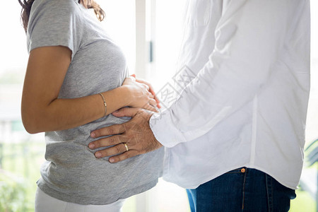站在家里的男人在女人子宫里感觉胎儿的腹部图片