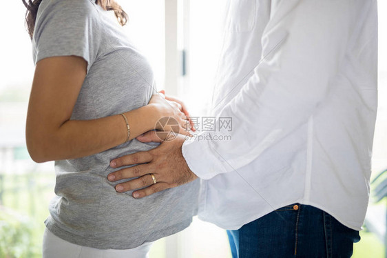 站在家里的男人在女人子宫里感觉胎儿的腹部图片