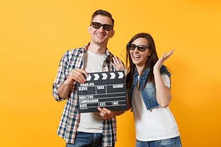 年轻的微笑夫妇的女人男人在3d眼镜看电影的日期举行的经典电影制作clapperboard和传播的手在黄色隔离图片