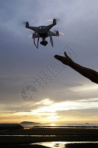 在日落天空背景下的手持无人机飞机图片