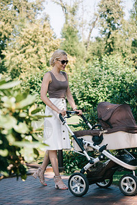 母亲与婴儿车在公园里散步背景图片