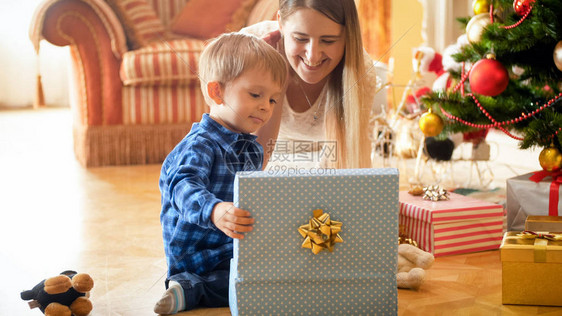 快乐微笑家庭的肖像与小男孩打开圣诞礼物图片