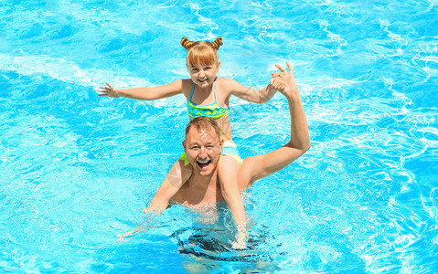 快乐的父亲与女儿在游泳池休息图片