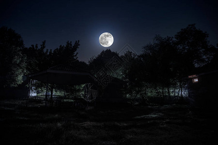 夜晚用月亮或老式乡村住宅在森林中建造的山夜景观夜晚用云彩和星星夏夜长时间曝光拍摄的照片图片