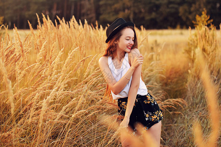 户外美女享受大自然漂亮的十几岁的模特戴着帽子在春天的阳光下奔跑麦田里浪漫的金发女孩吹长头发快乐的女孩微笑日落图片