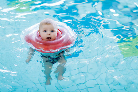 可爱的小宝贝孩子在室内游泳池里用游泳圈游泳新生女孩或男孩在水中玩乐婴幼儿积极健图片