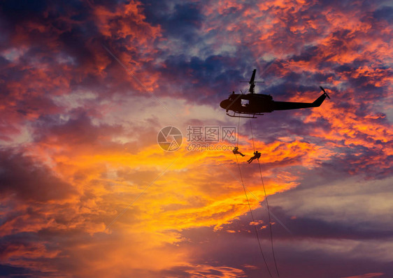 剪影战士在行动绳索从直升机攀登与军事使命反攻击训练在日落图片