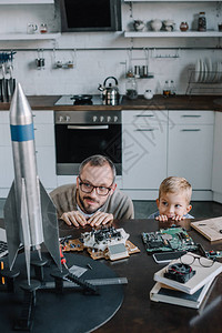 父亲和儿子看着从桌子在厨房和看火箭图片