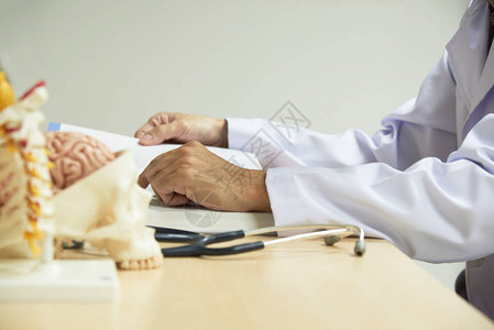医生坐在图书馆学习课本人脑与颈椎spineand听诊器模型的研究前景图片