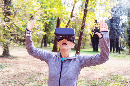 在森林里用虚拟现实耳机和老人用的VR装置给高龄女人带图片
