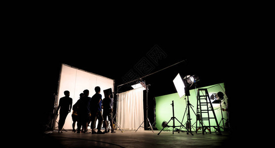 vdo制作的低关键剪影照明幕后电影摄制组团队正在设置摄像头并设置拍摄和等待电影导演同意与显示器中的场景图片