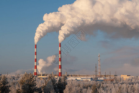 在寒冷的冬天火电厂的管道火电站高管道产生的白色浓烟在寒冷的冬日白色的蒸汽在蓝天上背景图片