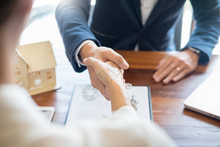房屋开发商代理人或财务顾问和客户在签署文件后握手作为与公司的成功协议合同图片