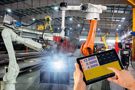 工程师用监控系统软件对智能工厂工业中的焊接机器人自动臂机进行检查和控制数字制造业务图片