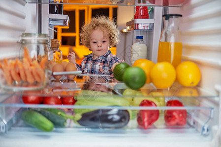 蹒跚学步的孩子从冰箱里偷食物从冰箱里拍的照片背景图片