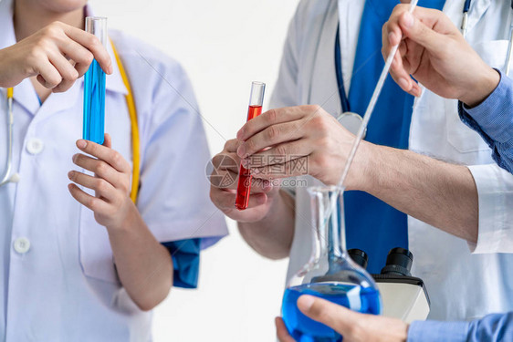 一组科学家穿着实验室外套在实验室工作同时检查试管和科学仪器中的生物化学样品科学技术研发理念图片