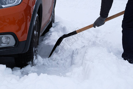 冬天雪车冬天下雪后男人在橘子车旁刷雪铲雪手里拿着铲子图片