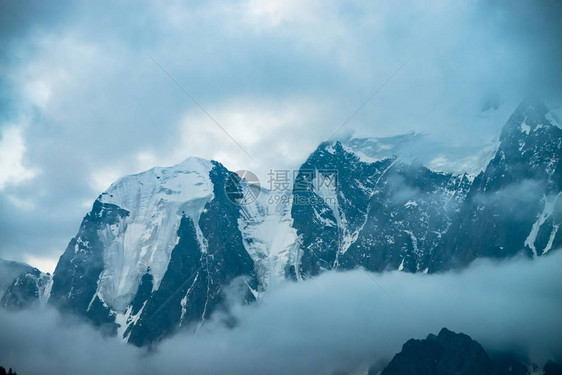 巨大冰川前的低云在多云的天空下巨大的雪山清晨山中的浓雾无法穿透的雾冰冷的岩石黑暗的大气景观图片